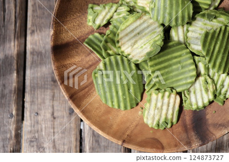 Jagged cut matcha chocolate potato chips served on an acacia plate Jagged cut matcha chocolate potato chips served on an acacia plate 124873727