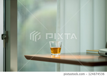 窗邊的玻璃杯和正在閱讀的書 124874536