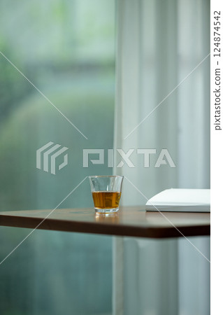 A glass by the window and a book being read A glass by the window and a book being read 124874542