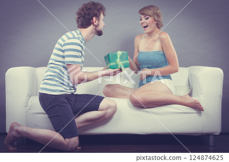 Young man giving woman gift box Young man giving woman gift box 124874625