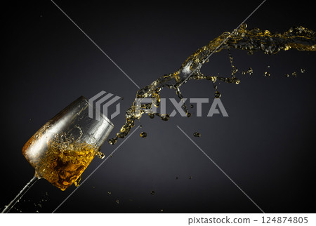 Glass and white wine splash on a black background. Glass and white wine splash on a black background. 124874805