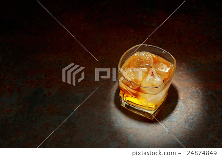 Whiskey in a square glass with ice on a vintage background. 124874849