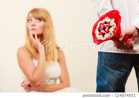 Man with candy bunch flowers and unhappy woman. Man with candy bunch flowers and unhappy woman. 124874851