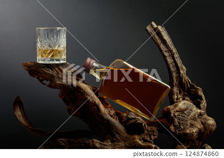 Bottle and glass of whiskey on a old snags. 124874860