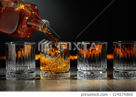 Whiskey is poured into a crystal glass. 124874868