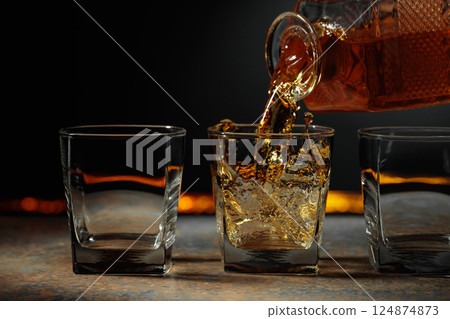 Whiskey is poured into a crystal glass. 124874873