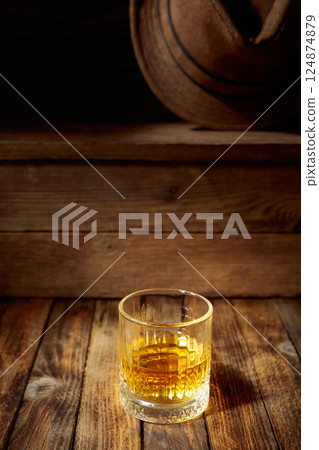 Elegant whiskey glass filled with amber liquid on a old wooden table. 124874879