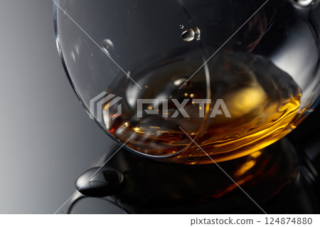 Glass of brandy on a black reflective background. Glass of brandy on a black reflective background. 124874880