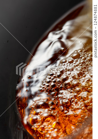 Golden drink is poured into the glass, creating beautiful waves and splashes. Golden drink is poured into the glass, creating beautiful waves and splashes. 124874881
