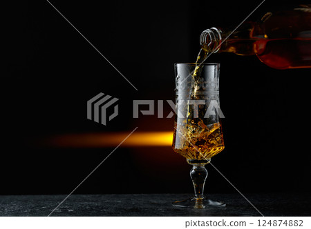 Hard liquor being poured into a glass. Hard liquor being poured into a glass. 124874882