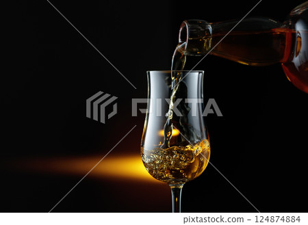 Rum being poured from a bottle into a glass. Rum being poured from a bottle into a glass. 124874884