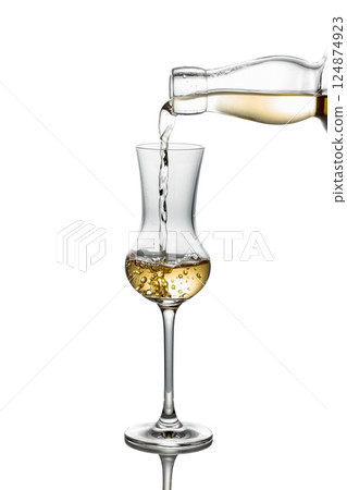 Gold liquor pouring into a glass on a white background. Gold liquor pouring into a glass on a white background. 124874923
