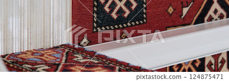Manufacturing process, weaving of a traditional wool oriental red carpet with an intricate floral pattern, decorative elements. banner Manufacturing process, weaving of a traditional wool oriental red carpet with an intricate floral pattern, decorative elements. banner 124875471