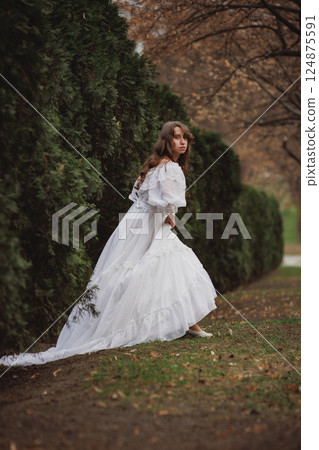 Woman clutching gown in dramatic movement turns her gaze, caught mid-step between fear and freedom. Woman clutching gown in dramatic movement turns her gaze, caught mid-step between fear and freedom. 124875591