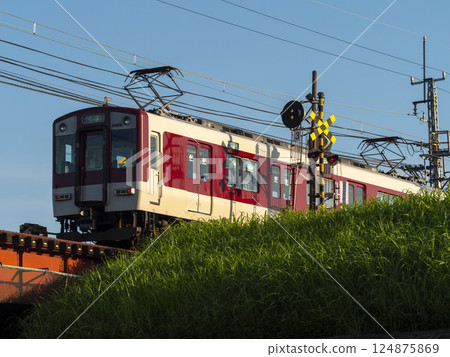 A Kintetsu Railway Myoji Line train passing through a railroad crossing on the Yamatogawa Embankment Road A Kintetsu Railway Myoji Line train passing through a railroad crossing on the Yamatogawa Embankment Road 124875869