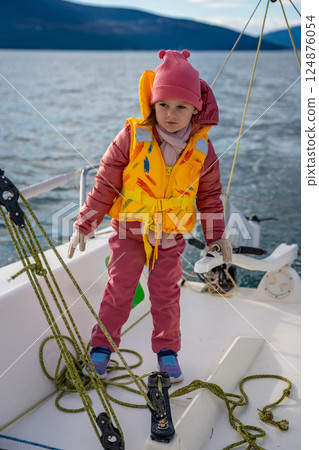 Little girl learning to sail a yacht during training in the Kotor Bay, Montenegro, representing adventure, freedom, and nautical sport. Little girl learning to sail a yacht during training in the Kotor Bay, Montenegro, representing adventure, freedom, and nautical sport. 124876054