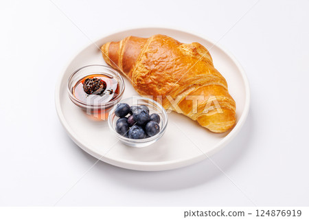 Flaky golden croissant served with fresh blueberries and a side of sweet berry jam 124876919