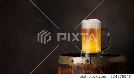 A glass of beer with a golden hue and frothy head 124876948