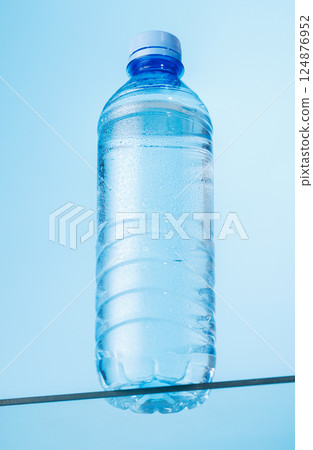 Bottle of water on a glass table against a vibrant blue background Bottle of water on a glass table against a vibrant blue background 124876952