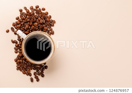 A steaming cup of freshly brewed coffee surrounded by rich, aromatic roasted coffee beans 124876957