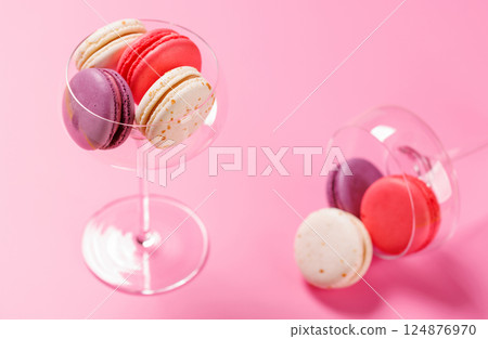 A delightful assortment of colorful macaroons arranged on a vibrant pink background A delightful assortment of colorful macaroons arranged on a vibrant pink background 124876970