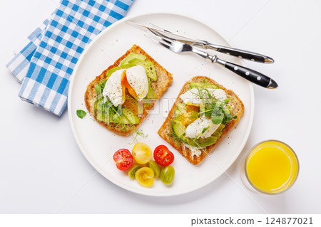 Delicious avocado toasts topped with perfectly cooked poached eggs Delicious avocado toasts topped with perfectly cooked poached eggs 124877021