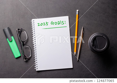 Elegant leather desk setup with coffee, stationery, and a notepad labeled 2025 Goals 124877065