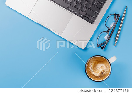 A clean and minimal desk setup featuring a laptop and a coffee cup 124877186