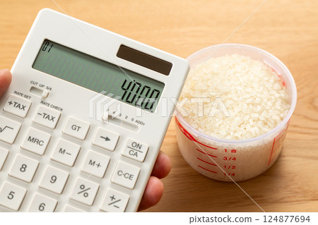 手拿著量杯的米和一個計算器 手拿著量杯的米和一個計算器 124877694
