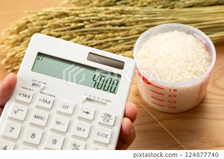 手拿著量杯的米和一個計算器 124877740