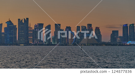 Doha, Qatar-March 21, 2025:  Doha Qatar skyline from the Corniche street at dusk with dhows in the Arabic gulf in the foreground 124877836