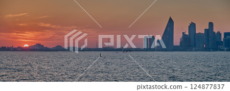 Doha, Qatar-March 21, 2025:  Doha Qatar skyline from the Corniche street at dusk with dhows in the Arabic gulf in the foreground 124877837