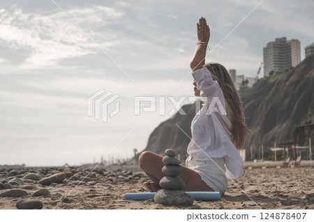 Young woman meditating on a rocky beach during summertime Young woman meditating on a rocky beach during summertime 124878407