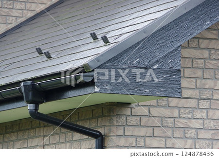 The paint on the gable is deteriorating and peeling off. 124878436