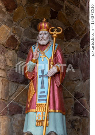 Colorful statue of a saint wearing a crown and holding a staff in a stone alcove in a historical site during daylight Colorful statue of a saint wearing a crown and holding a staff in a stone alcove in a historical site during daylight 124878530