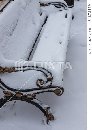Snow-covered bench in a quiet park during winter, creating a serene and peaceful atmosphere for visitors Snow-covered bench in a quiet park during winter, creating a serene and peaceful atmosphere for visitors 124878539