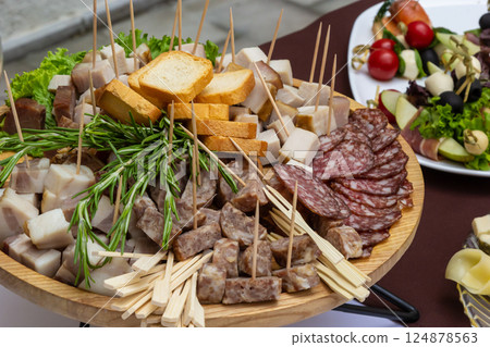 Variety of cured meats and cheeses served on a large platter during a culinary event in an outdoor setting 124878563