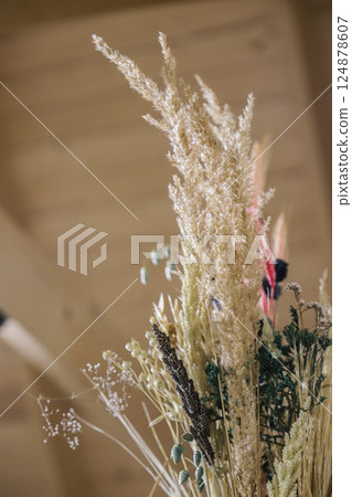 Decorative arrangement of dried grasses and flowers in a cozy interior setting showcasing natural textures and earthy tones during daylight 124878607