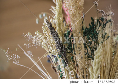 Dried flower arrangement featuring a diverse mix of textures and colors on display in a cozy indoor setting 124878608