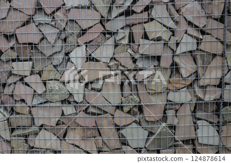 Collection of irregular stone pieces held in a wire mesh, used for landscaping and building projects in a construction setting Collection of irregular stone pieces held in a wire mesh, used for landscaping and building projects in a construction setting 124878614