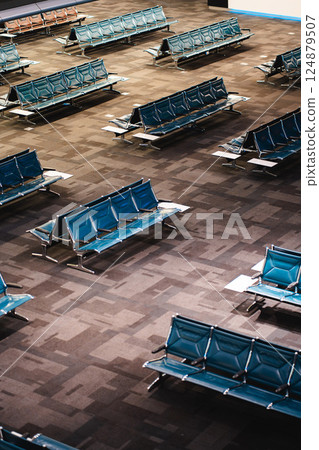 Modern Airport Waiting Area with Rows of Blue Seats, Spacious Terminal Lounge Featuring Contemporary Chair Arrangements 124879507