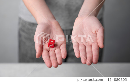Red die in child's hand symbolizing chance and decision making concept. 124880803