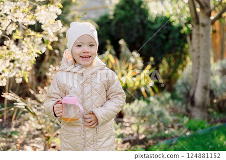 Smiling child in blooming spring garden. Portrait of beauty girl Smiling child in blooming spring garden. Portrait of beauty girl 124881152