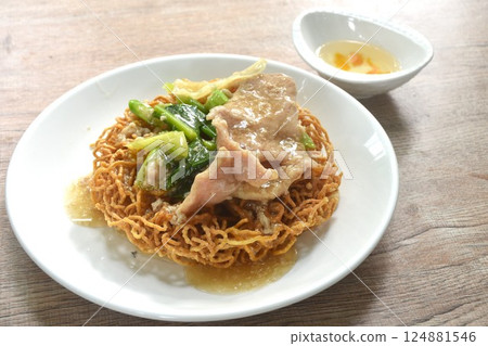 crispy fried egg noodle with slice soft marinated pork and Chinese kale dressing gravy sauce on plate couple vinegar chili cup 124881546