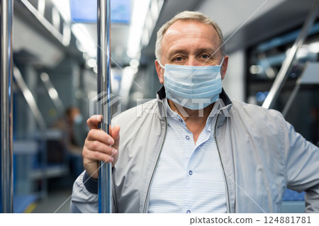 Middle aged man in face mask in subway car Middle aged man in face mask in subway car 124881781