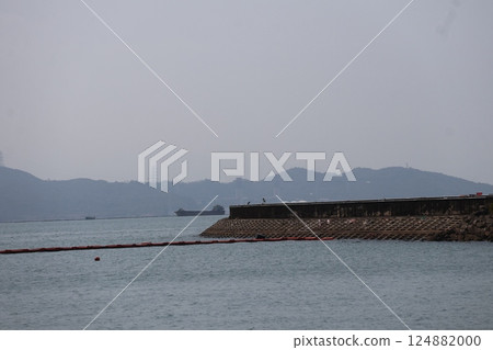 A landscape with the sky, the hazy mountains on the opposite bank, the sea, a boat, and a jetty 124882000