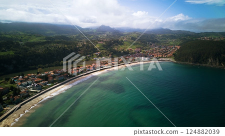 Aerial drone view of coastal town and beach with turquoise water, green hills and mountains in Ribadesella, Asturias, Spain 124882039
