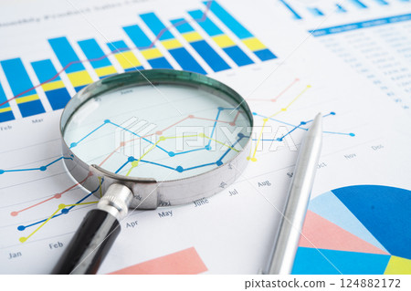 Magnifying glass on spreadsheet and graph paper. Financial data economy, Business. 124882172