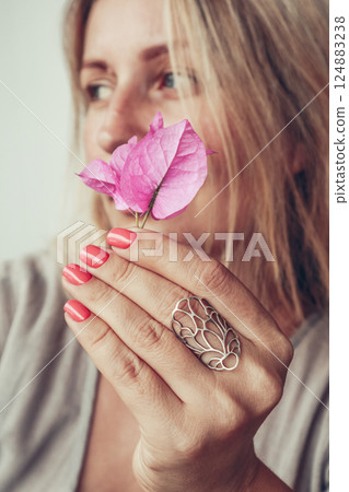 Beautiful mid age woman showing red shellac manicure on nails with flower 124883238