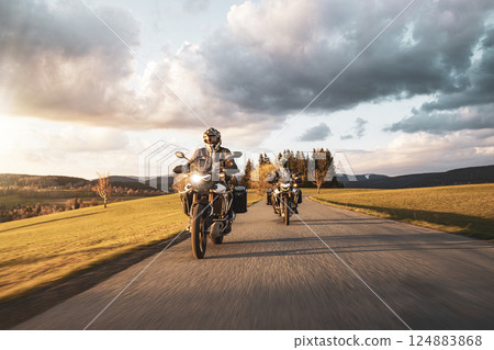 Two Drivers Riding Motorcycle on Empty Road During Sunset. Two Drivers Riding Motorcycle on Empty Road During Sunset. 124883868